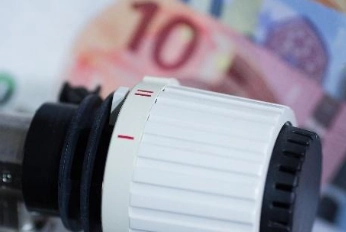Nahaufnahme eines weißen Thermostatreglers mit Euro-Geldscheinen im Hintergrund